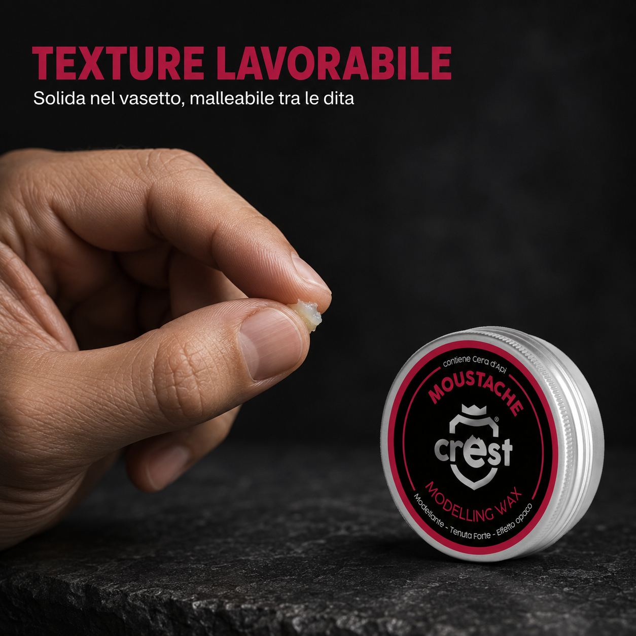 Mano che lavora una piccola quantità di CREST Moustache Wax accanto al vasetto argentato, per mostrare la texture malleabile.